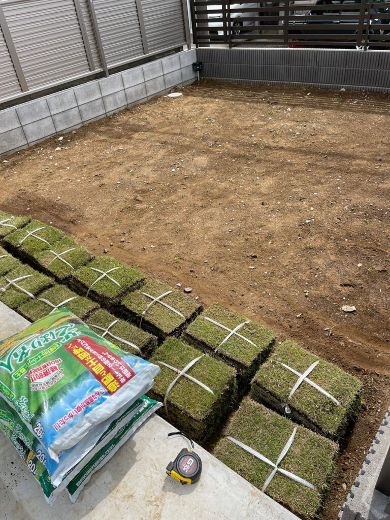 張る前の芝の束と、ならした土